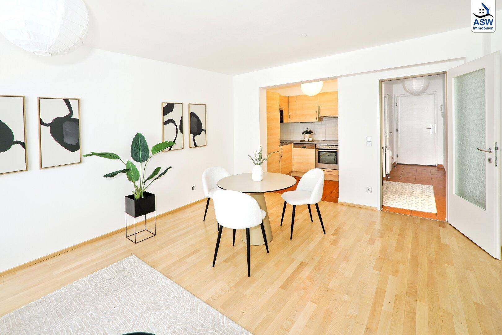 Geräumiger Wohnbereich mit Parkettboden, Essplatz und Blick in die angrenzende Küche.