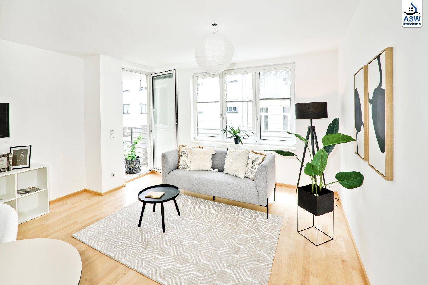 Helles Wohnzimmer mit modernem Sofa, Teppich und direktem Zugang zum Balkon.
