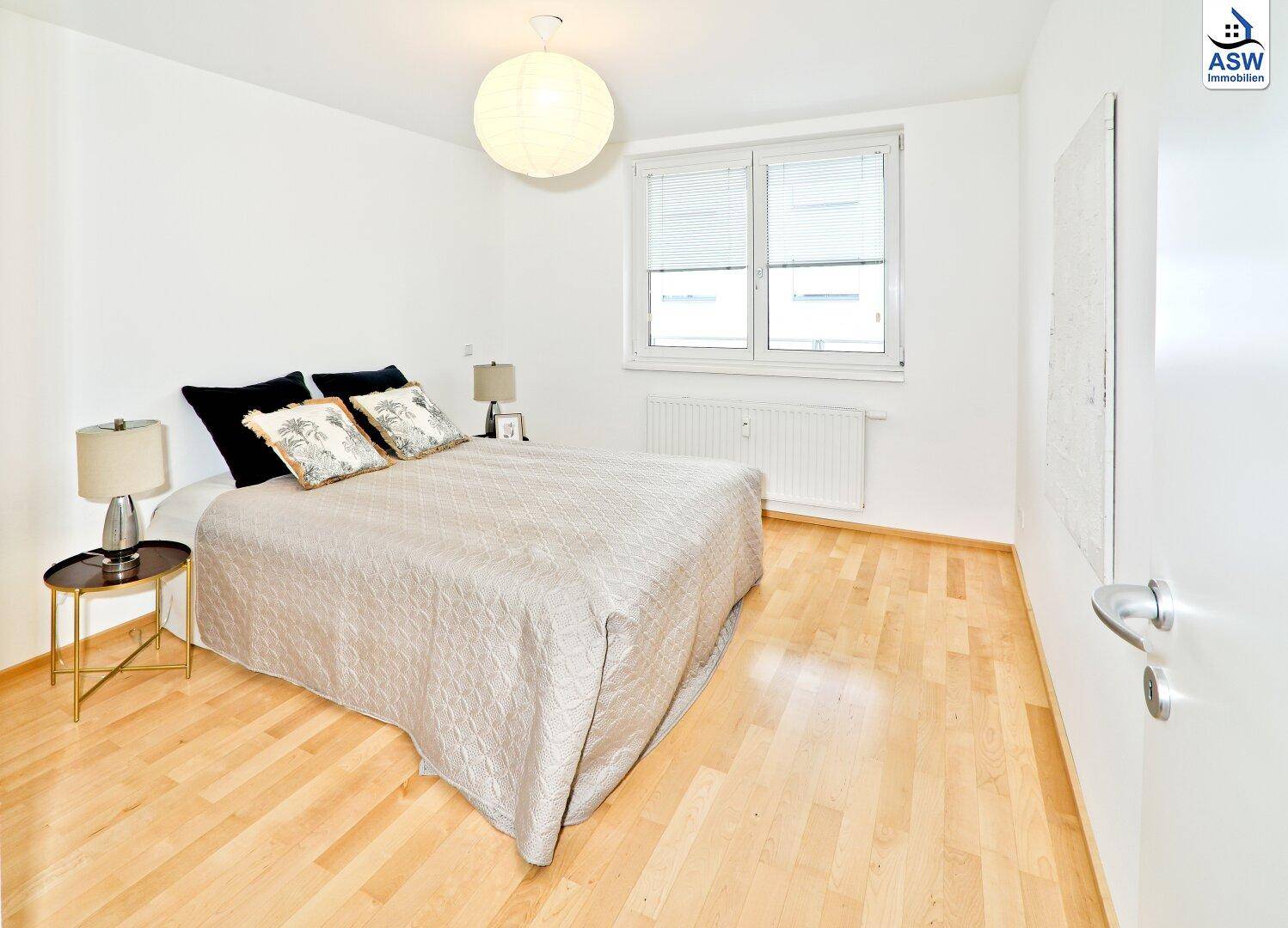 Ruhiges Schlafzimmer mit Doppelbett, Parkettboden und großem Fenster.