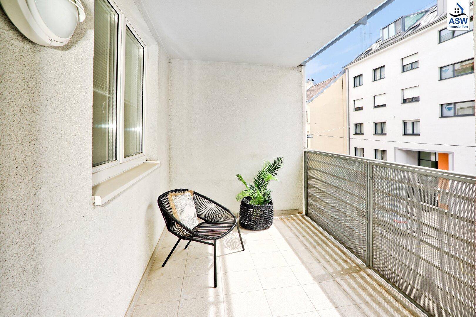 Sonniger Balkon mit Fliesenboden, bequemer Sitzgelegenheit und Blick auf die Stadt.