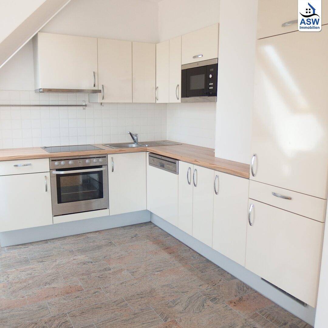 Moderne Einbauküche mit hellen Schränken, Holz-Arbeitsplatten und integrierten Geräten.