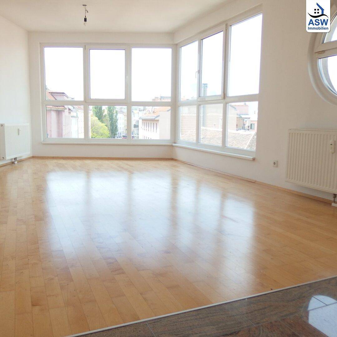 Geräumiges Wohnzimmer mit Holzboden und einer Fensterfront, die einen weiten Blick bietet.