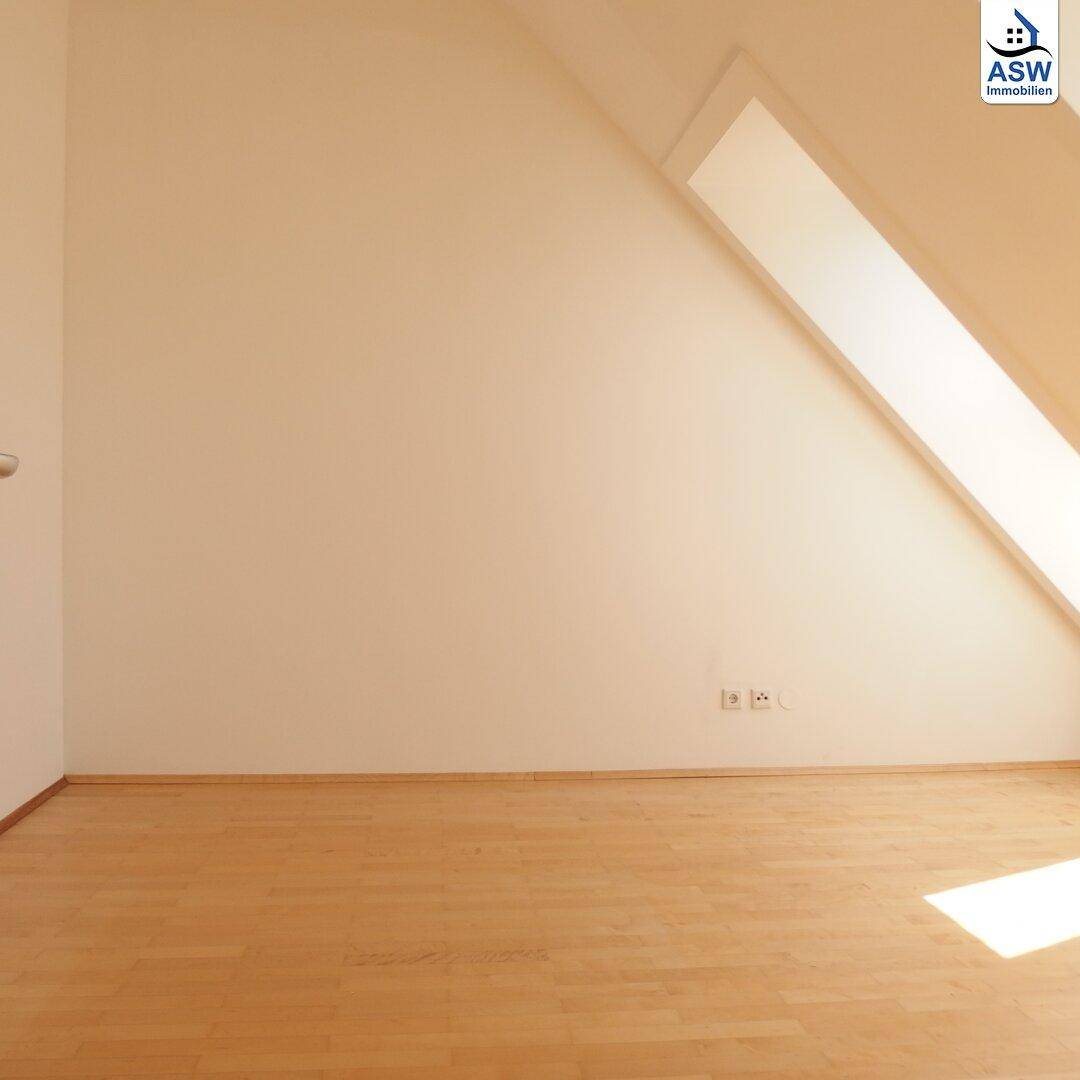 Geräumiger Raum mit Dachschräge und Holzboden, ideal als Schlafzimmer oder Arbeitsbereich nutzbar.