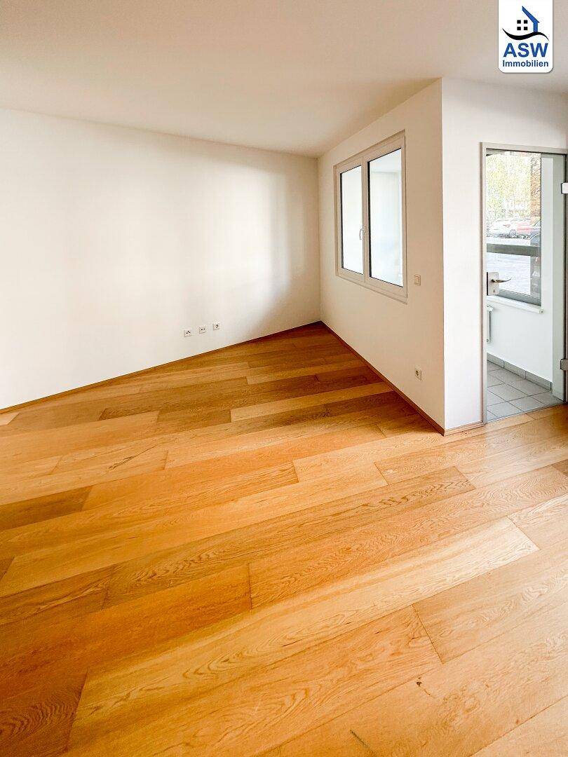 Geräumiges Zimmer mit hellem Holzfußboden und einem Fenster, das viel Licht hereinlässt.