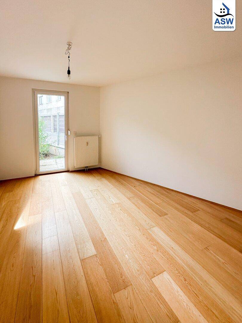 Heller Raum mit Holzfußboden und Zugang zu einem kleinen Außenbereich.