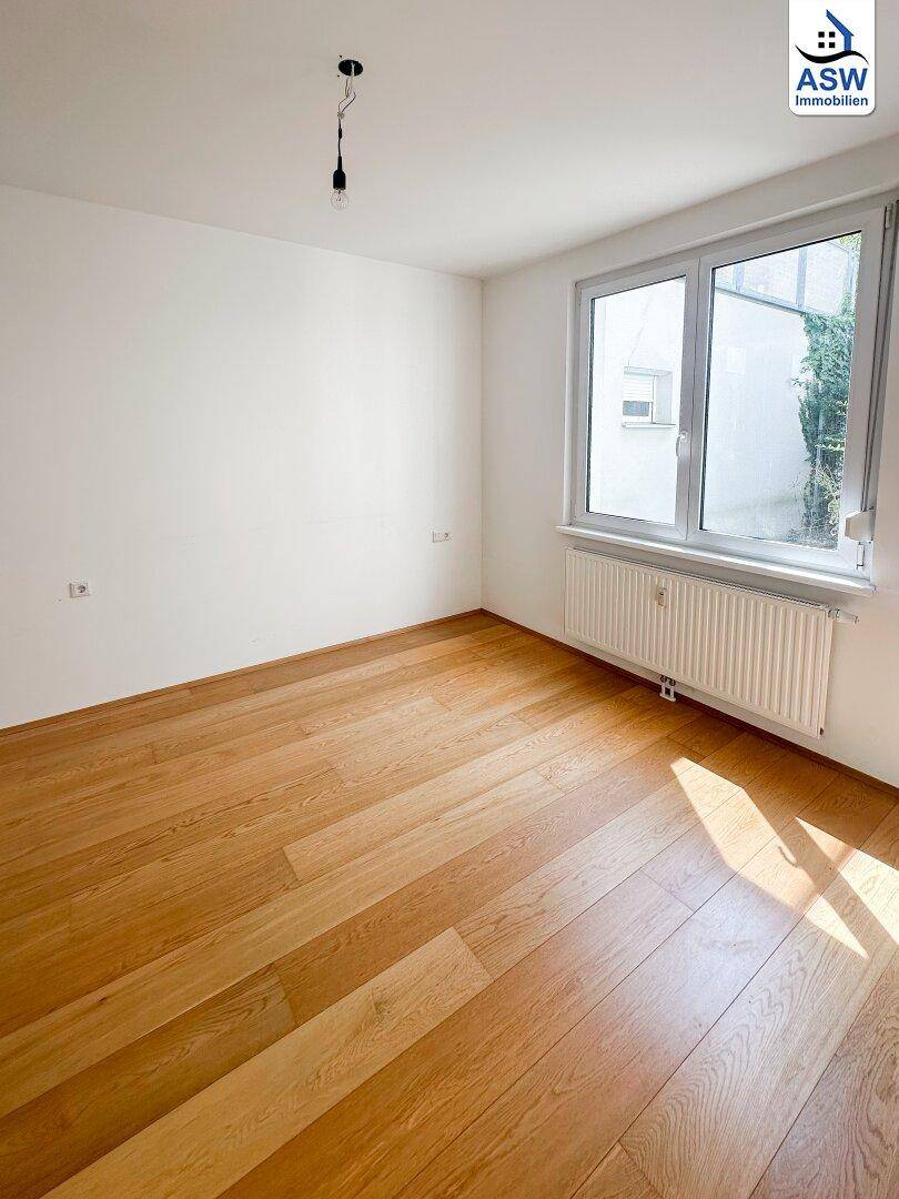 Freundliches Schlafzimmer mit Parkettboden und großem Fenster für viel Licht, ideal zum Entspannen.