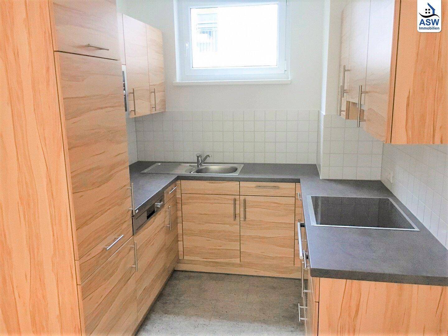Moderne Einbauküche mit hellen Holzfronten, dunkler Arbeitsplatte und integrierten Geräten.