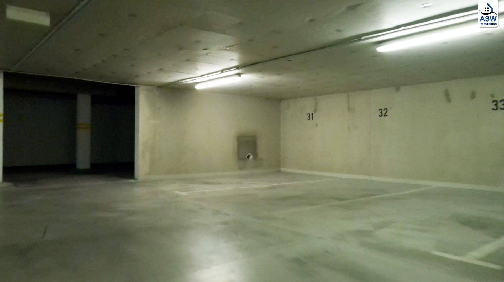 Saubere und gut beleuchtete Tiefgarage mit markierten Parkplätzen und Betonwänden.