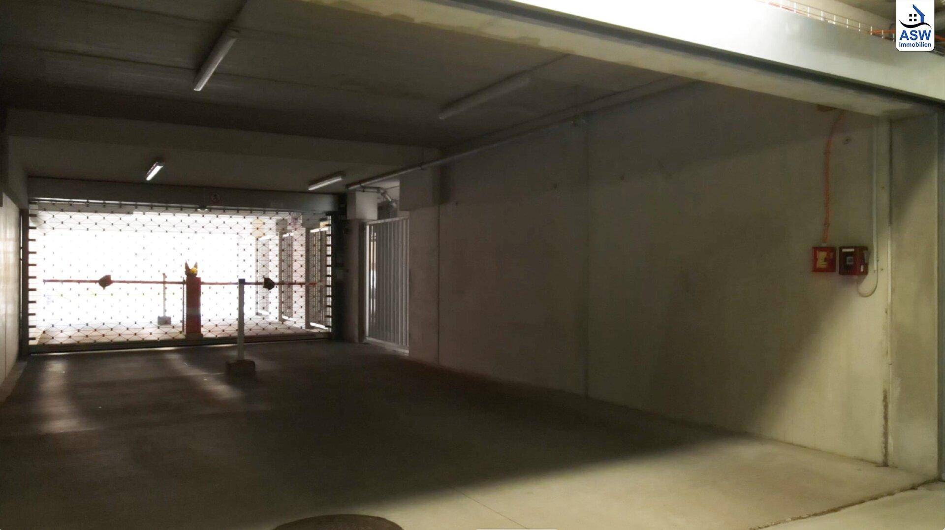 Einfahrt zur Tiefgarage mit Rolltor und Schranke für sicheren und kontrollierten Zugang.