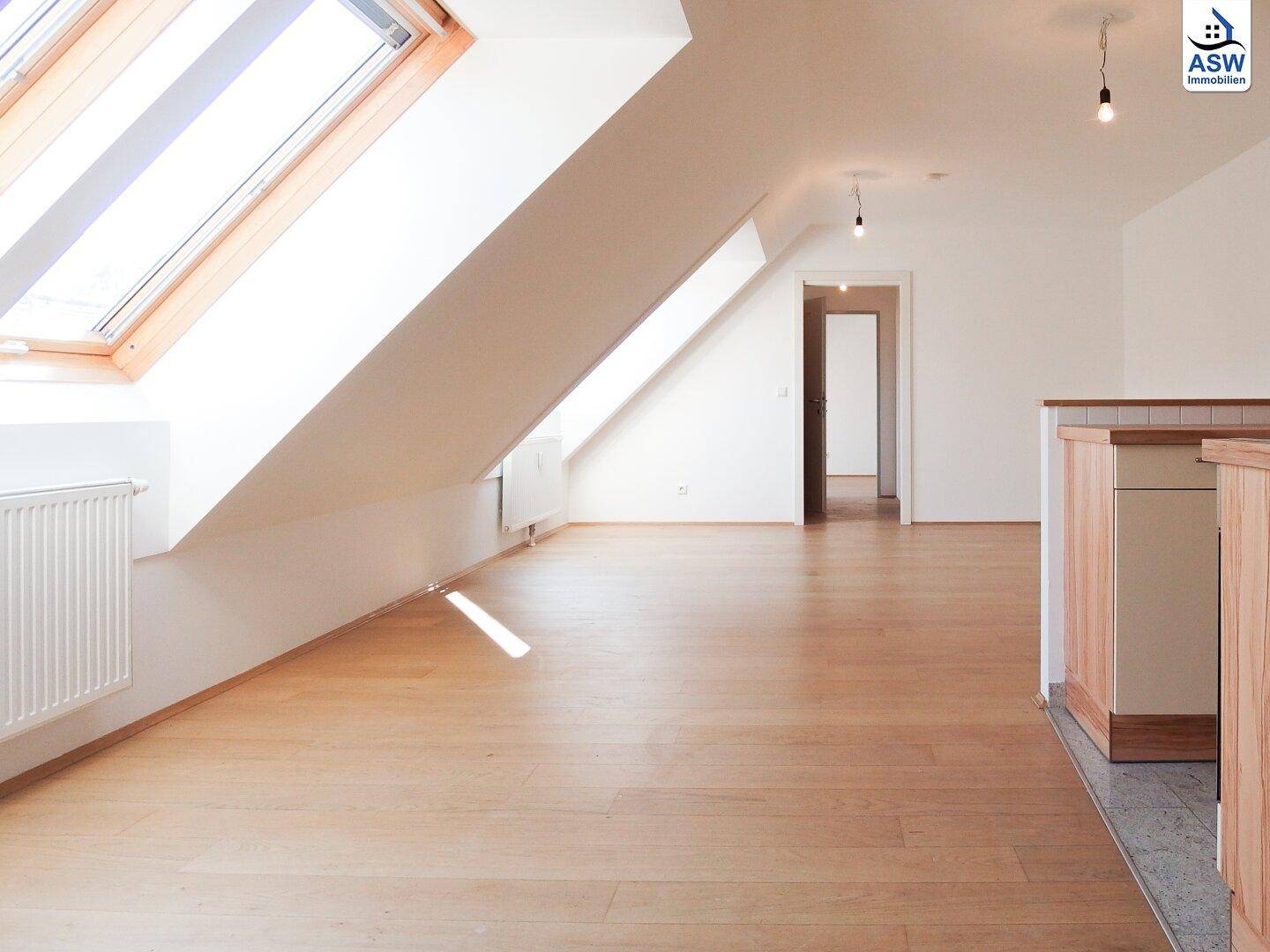 Geräumiges Dachgeschosszimmer mit Holzboden und viel Tageslicht, Blick auf den Flur.