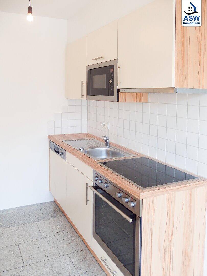 Moderne Küchenzeile mit integrierten Geräten, Kochfeld und Spüle, ideal für kleine Wohnungen.