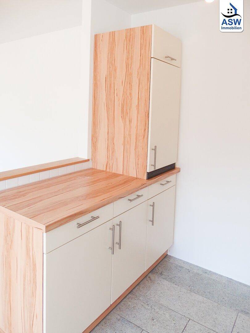 Küchenzeile mit Holz-Arbeitsplatte und integriertem Kühlschrank in hellem Design.