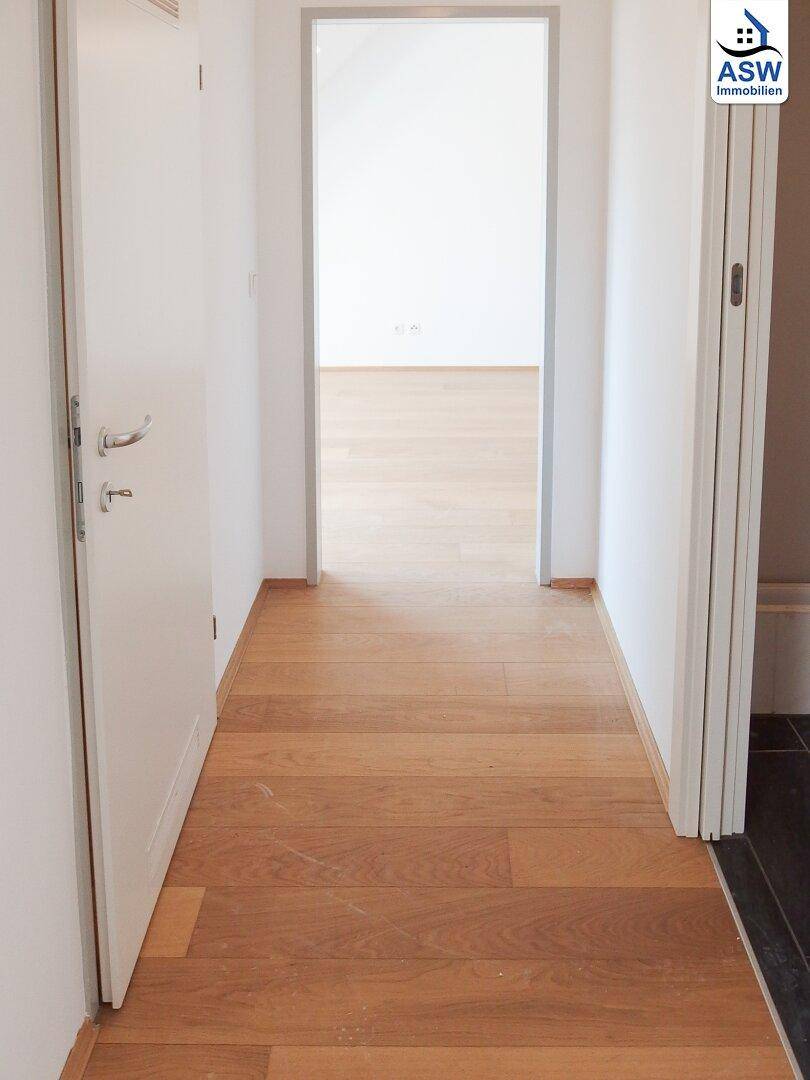 Heller Flur mit Holzboden, der zu weiteren Zimmern führt.