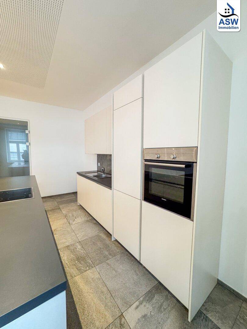 Elegante Einbauküche mit integriertem Backofen und modernen weißen Schränken.