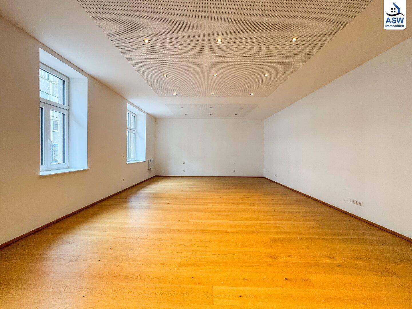 Heller, leerer Wohnbereich mit glänzendem Holzboden und hohen Decken, bereit zur individuellen Gestaltung.