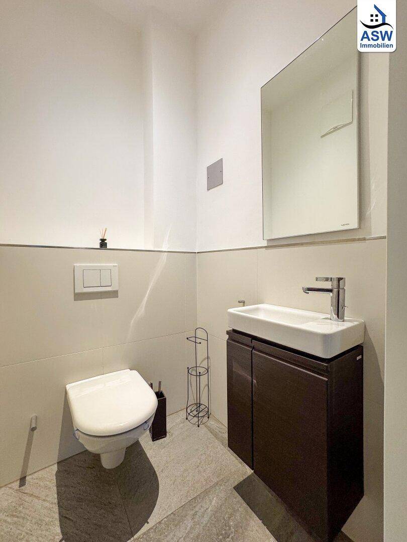 Helles Gäste-WC mit modernem Waschbecken, Spiegel und wandhängender Toilette.