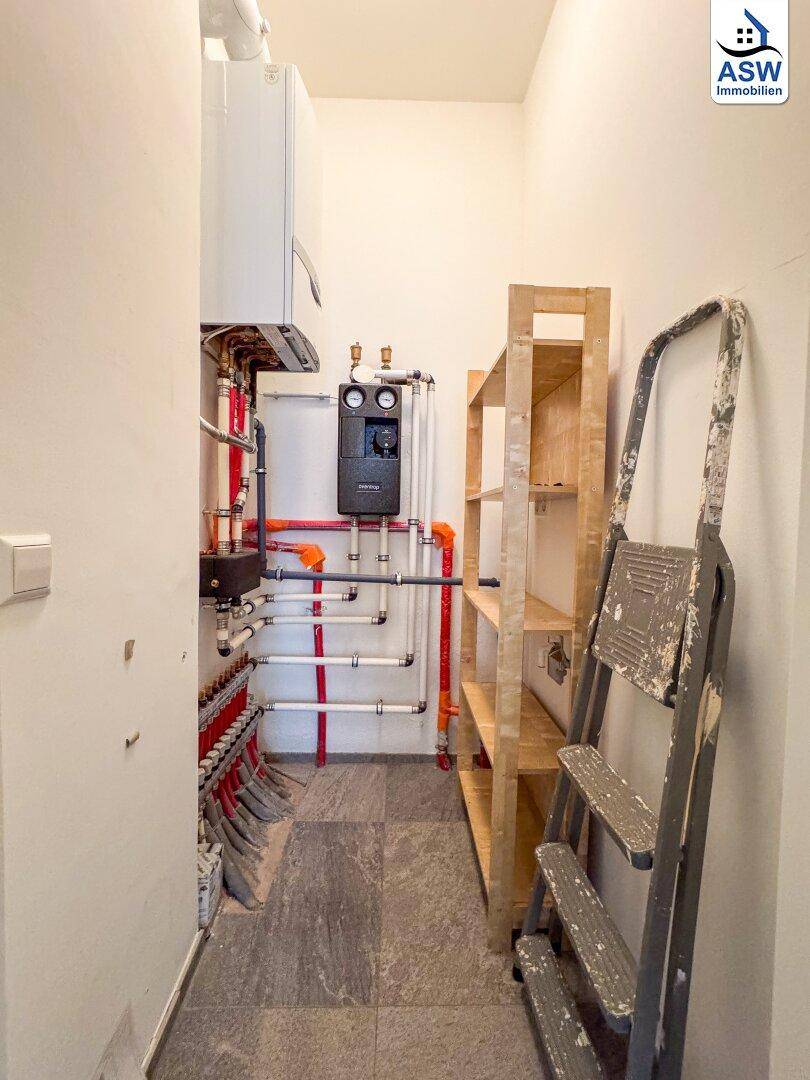 Praktischer Hauswirtschaftsraum mit Heizungsanlage, sichtbaren Rohren und Holzregalen für Stauraum.