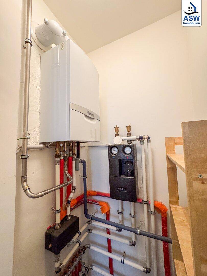 Detailansicht der modernen Heizungsanlage und der gut organisierten Rohrleitungen im Technikraum.