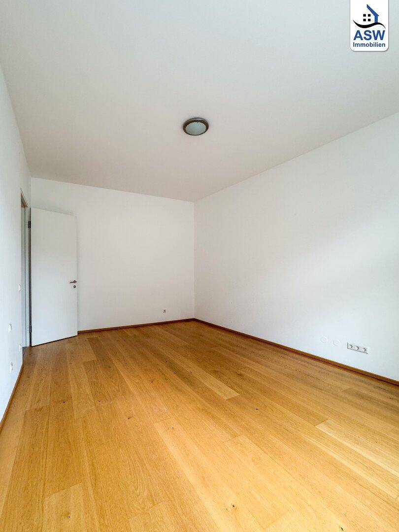 Leeres Zimmer mit Holzboden und weißer Tür, ideal als Schlafzimmer oder Arbeitszimmer nutzbar.
