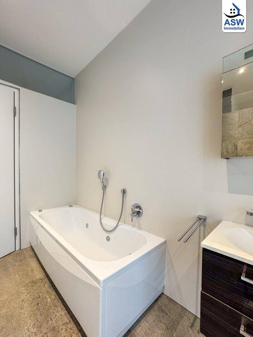 Elegantes Badezimmer mit moderner Badewanne, Einzelwaschbecken und beheiztem Handtuchhalter.