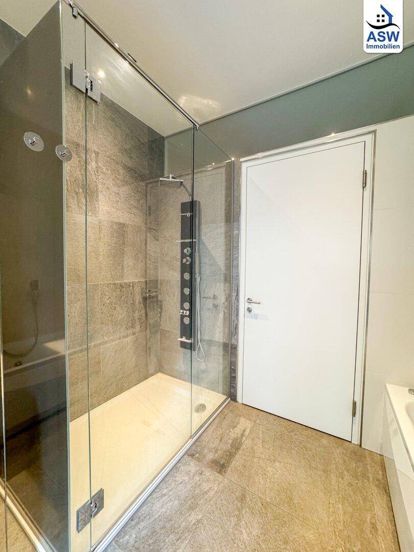 Große begehbare Dusche mit Glasabtrennung und modernem Duschpaneel.
