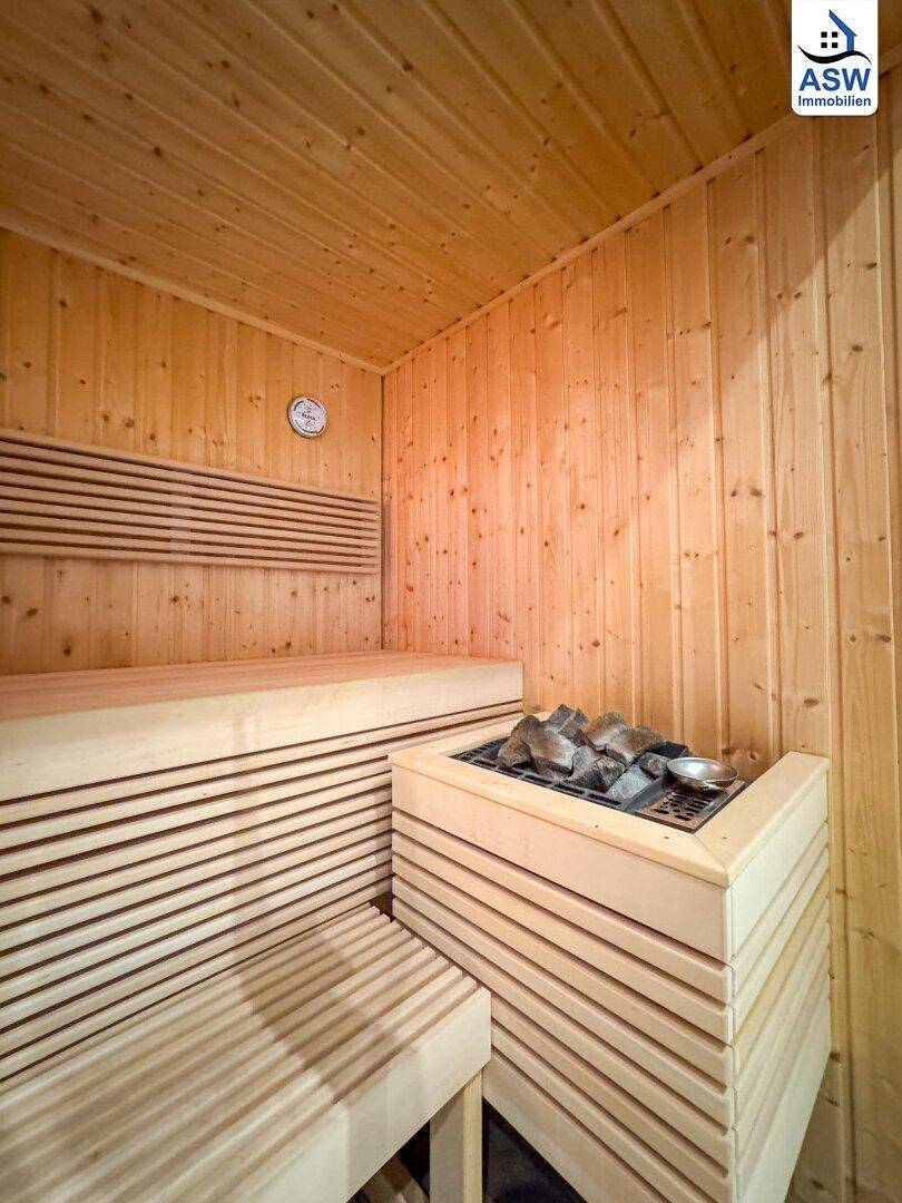Innenansicht der Sauna mit Holzverkleidung, bequemen Bänken und dem Saunaofen.