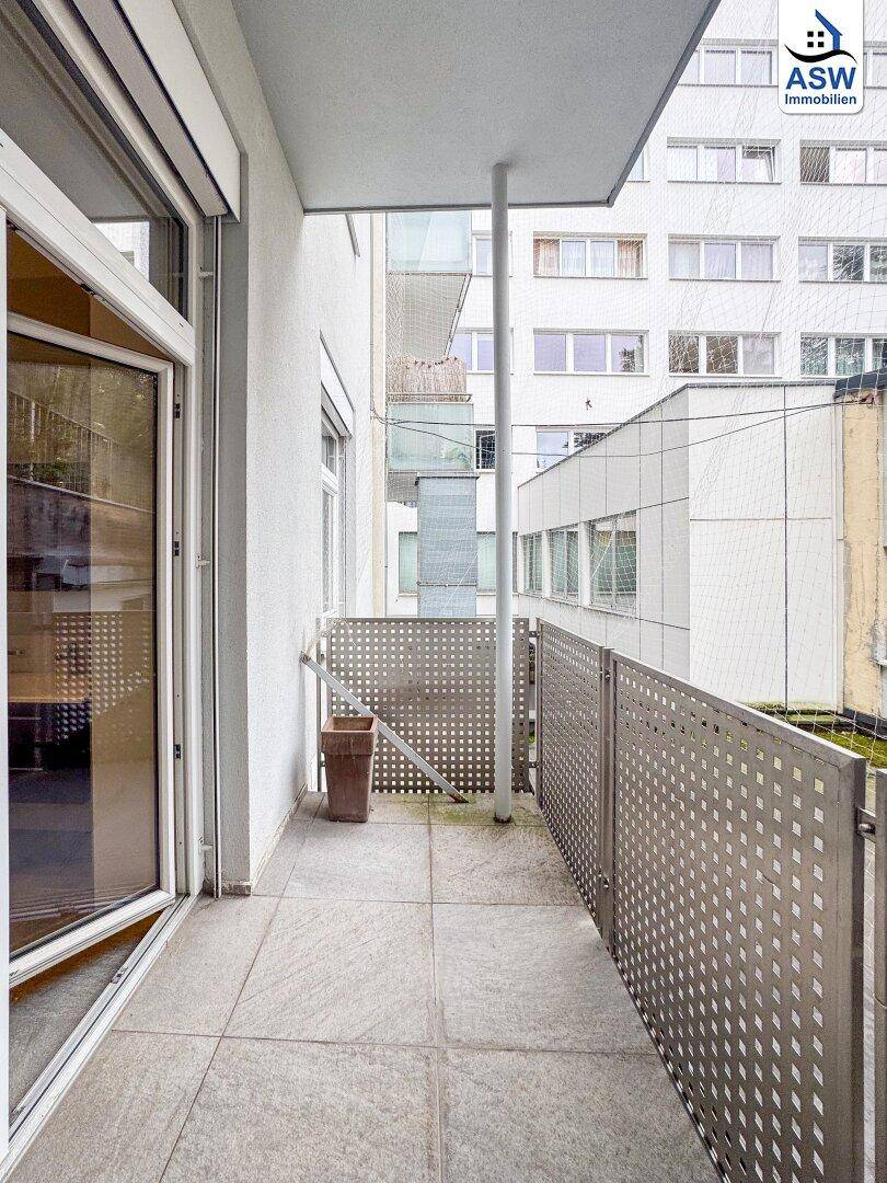 Heller Balkon mit Fliesenboden und Blick auf die umliegenden modernen Stadtgebäude.