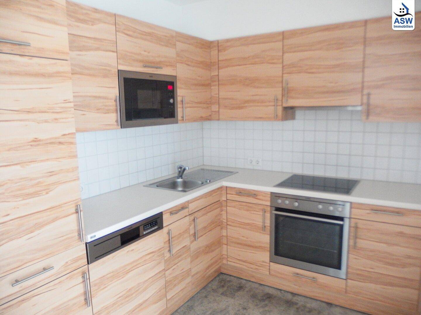 Moderne Einbauküche mit Holzfronten, weißer Arbeitsplatte und integrierten Geräten.