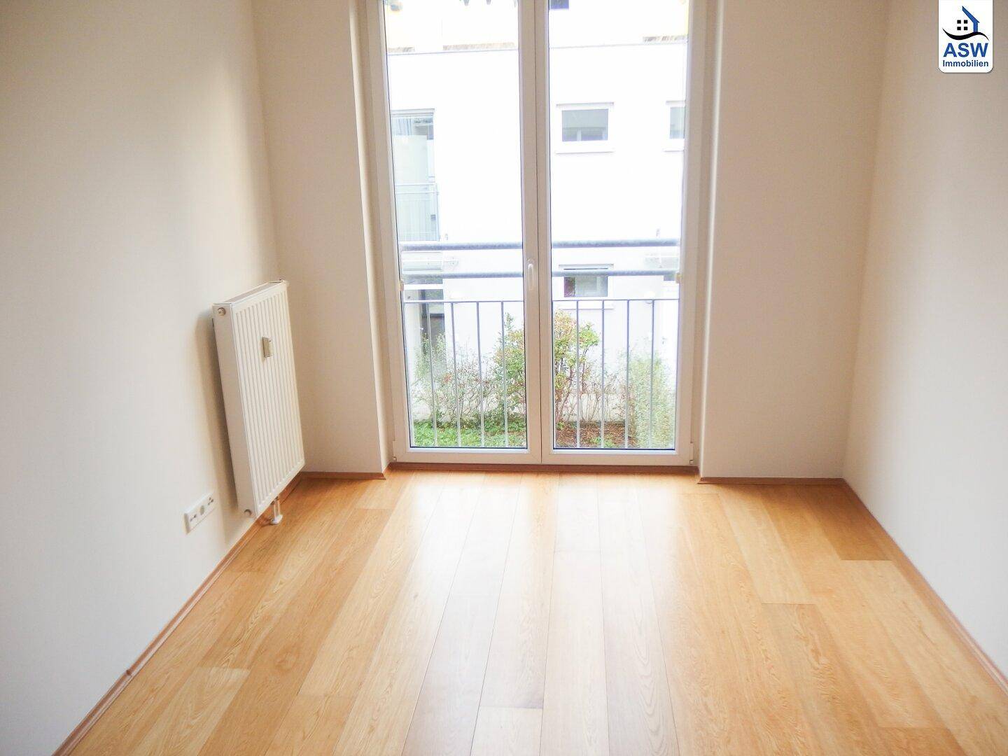 Helles Schlafzimmer mit Holzboden, weiß gestrichenen Wänden und französischem Balkon.