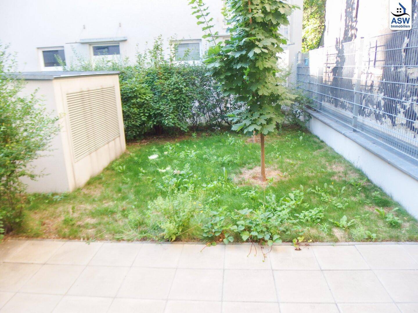 Kleiner privater Gartenbereich mit Rasenfläche und gepflasterter Terrasse.