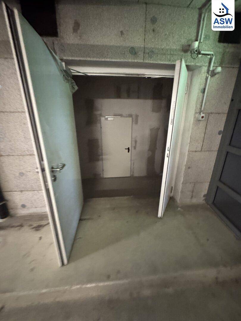Offene Tür zu einem Lagerraum in einer Tiefgarage, mit Blick auf den dahinterliegenden Betonraum.