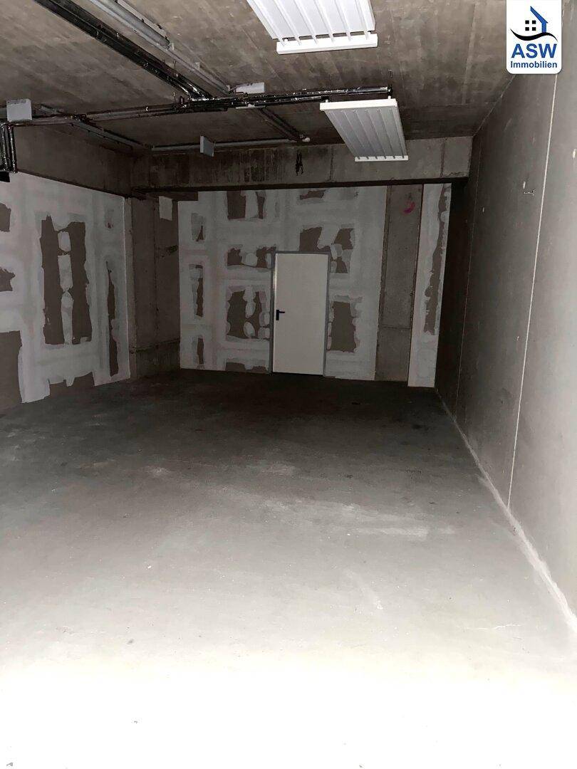Geräumiger, unfertiger Lagerraum im Keller mit Betonboden, unverputzten Wänden und einer einzelnen Tür.