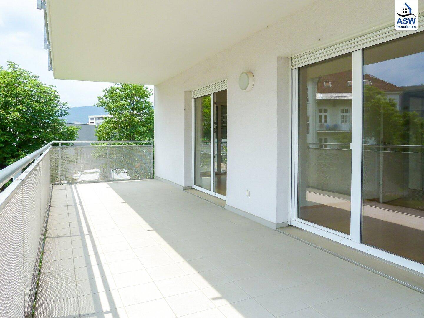Geräumiger Balkon mit Fliesenboden und Blick ins Grüne, ideal für entspannte Stunden im Freien.