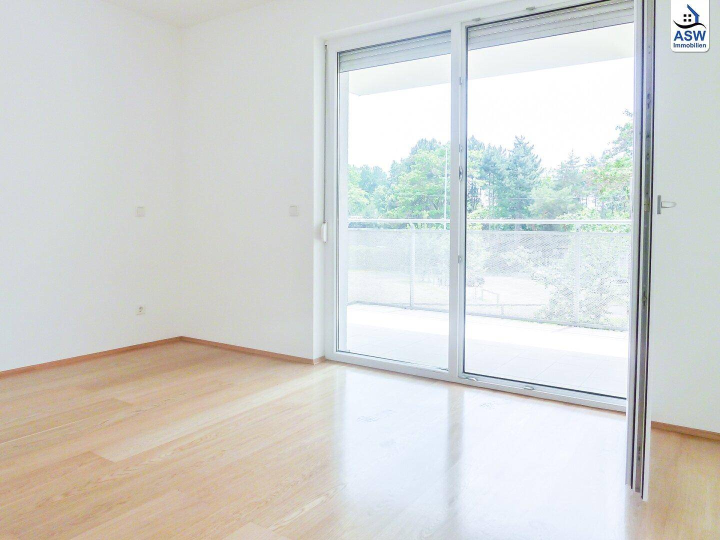 Schlafzimmer mit hellem Parkettboden und direktem Zugang zu einem Balkon oder einer Terrasse.
