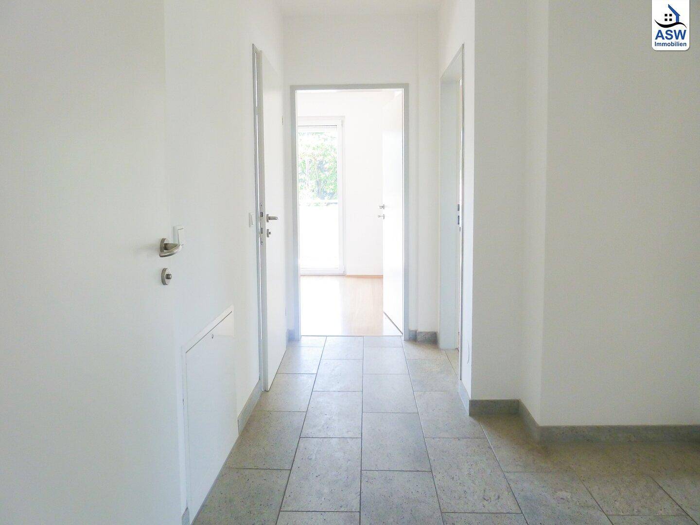 Heller Flur mit Fliesenboden und Zugang zu verschiedenen Räumen der Wohnung.