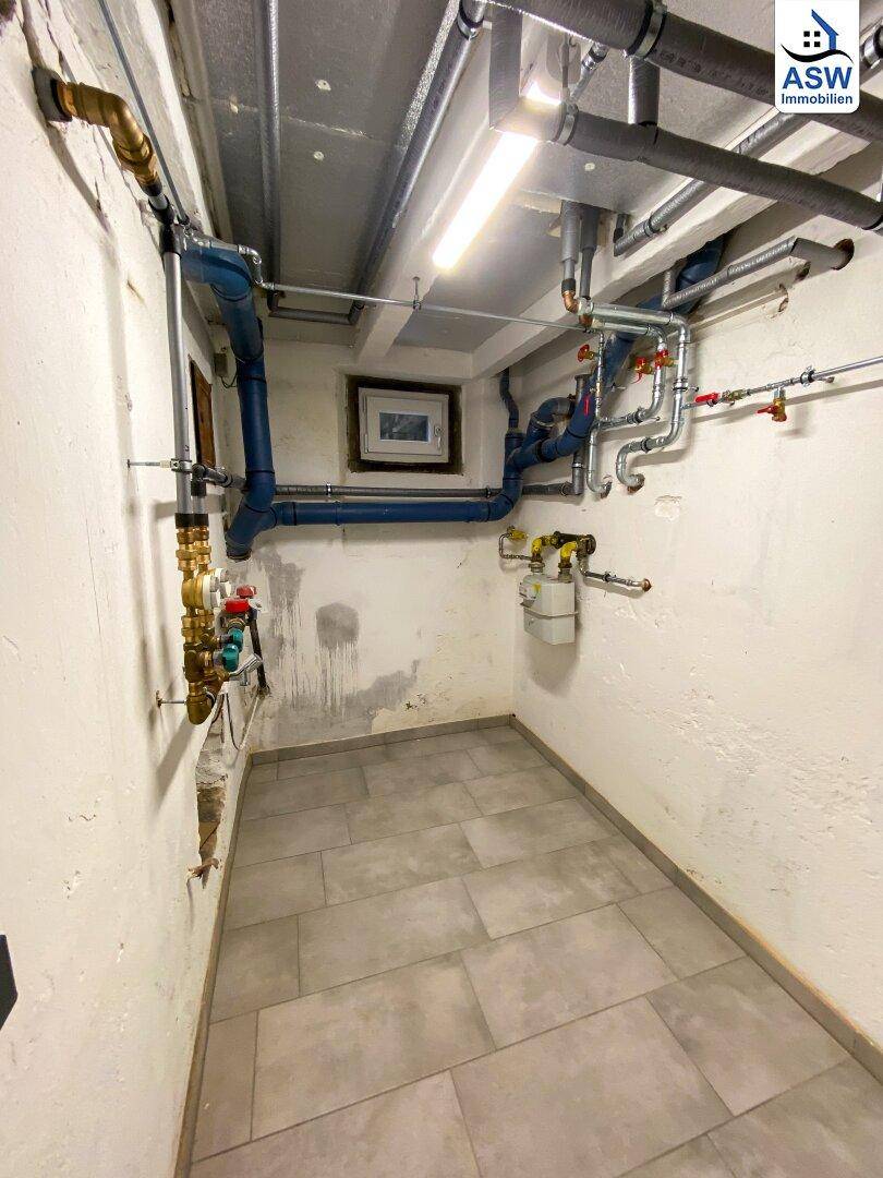 Kellerraum mit Fliesenboden und sichtbaren Versorgungsleitungen, geeignet als Technik- oder Abstellraum.