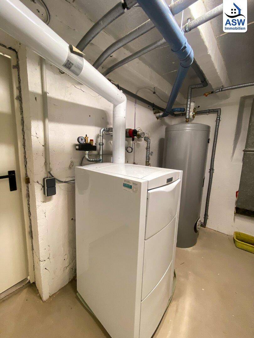Heizungsraum im Keller mit moderner Heizungsanlage und Warmwasserspeicher.