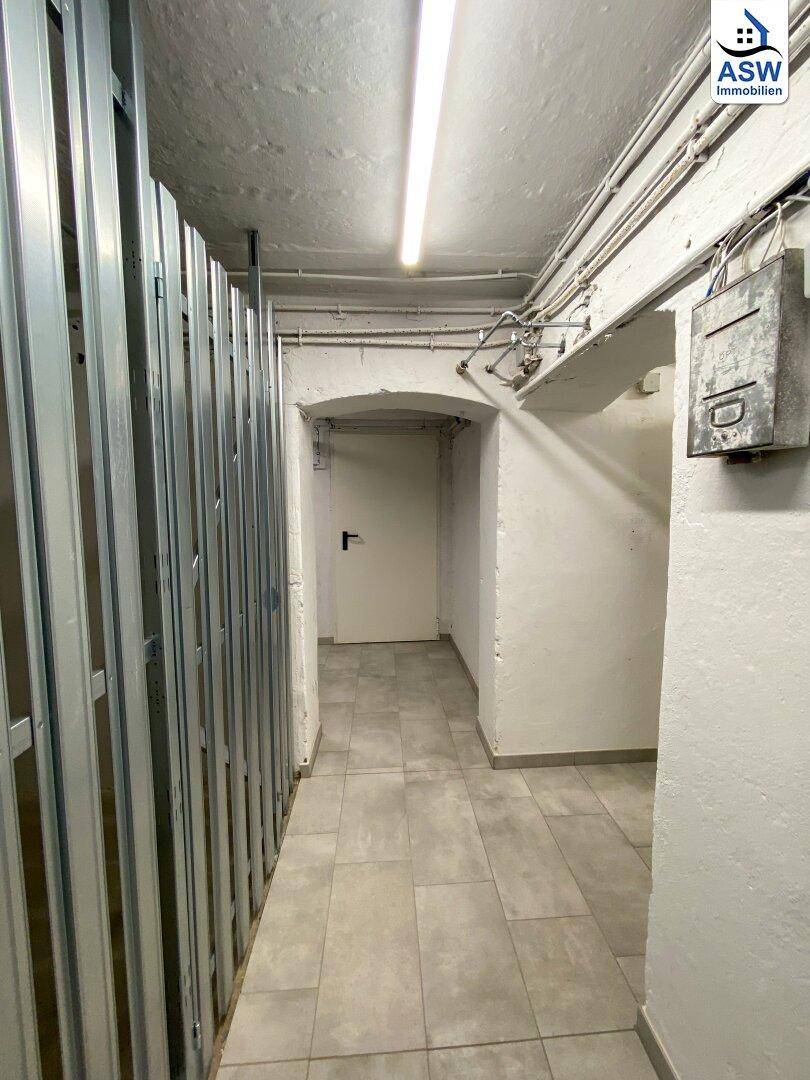 Kellerflur mit Fliesenboden und individuellen Abstellbereichen, ideal für zusätzlichen Stauraum.