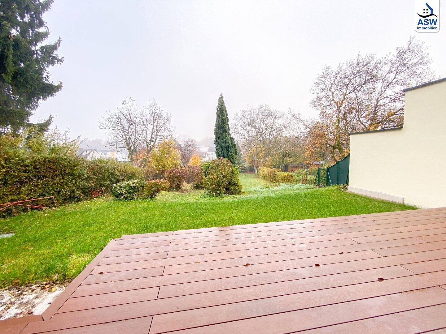 Geräumige Holzterrasse mit Blick auf den grünen Garten und die umliegende Natur.