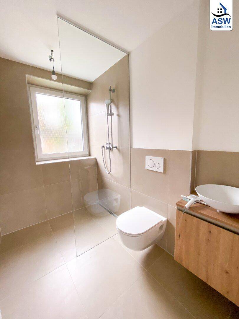 Modernes Badezimmer mit begehbarer Dusche, Wand-WC und Einzelwaschbecken.