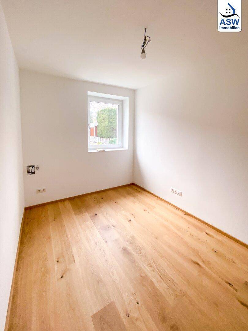 Gemütliches Schlafzimmer mit Eichenparkett und einem Fenster mit Blick ins Grüne.