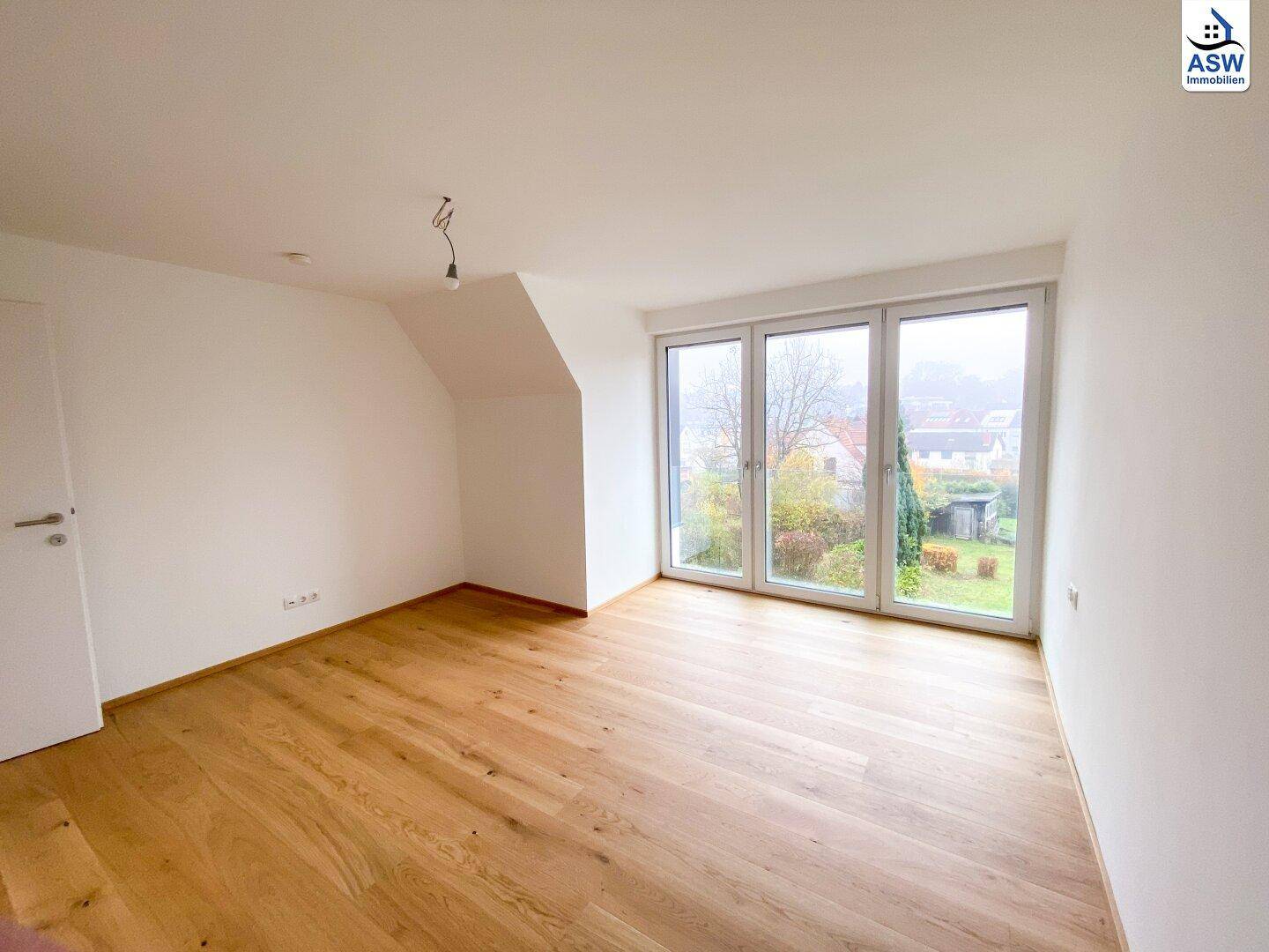 Geräumiges Schlafzimmer im Dachgeschoss mit Eichenparkett und großen Fenstern zum Garten.