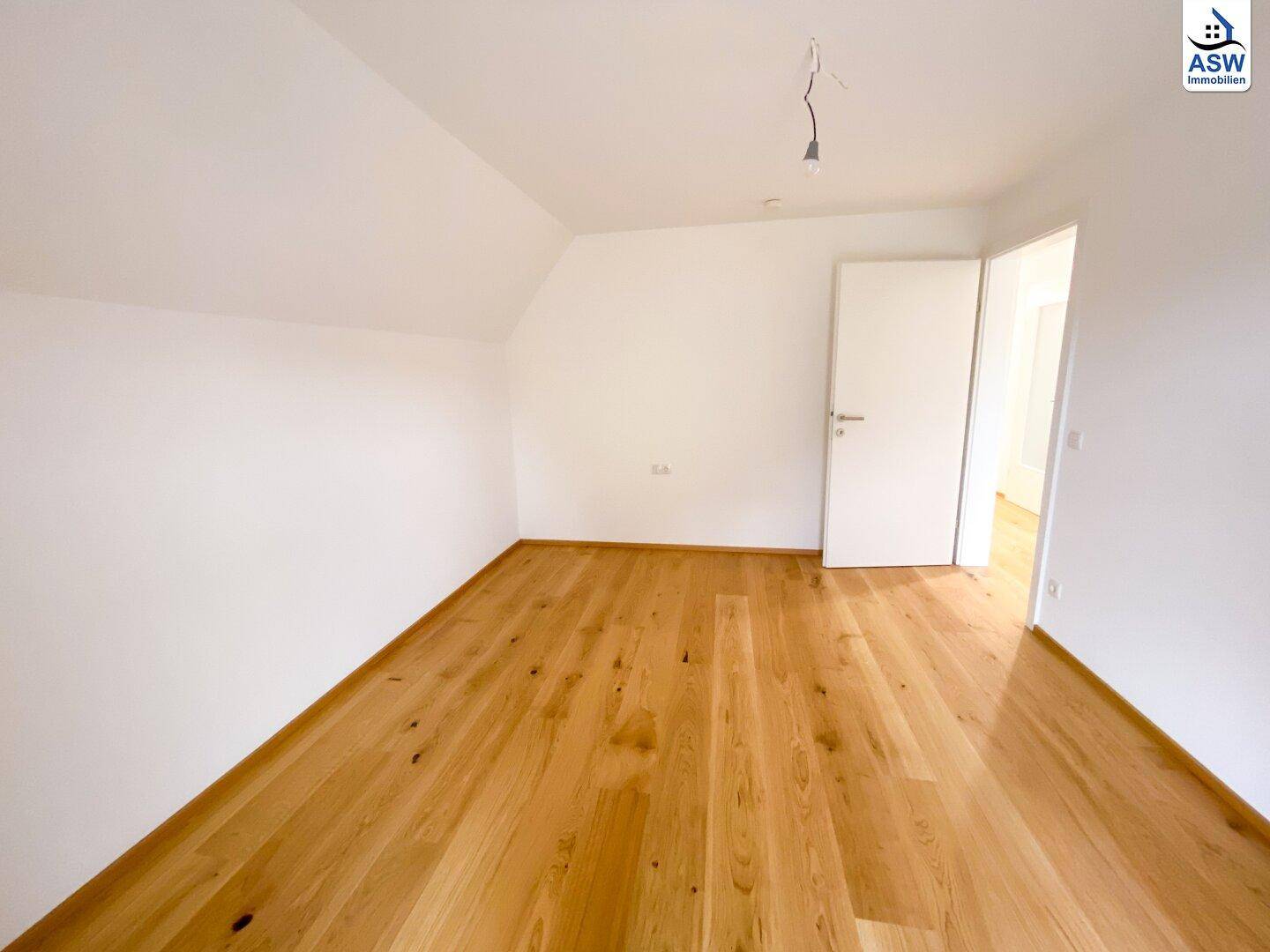Helles Schlafzimmer im Dachgeschoss mit Eichenparkett und weiß gestrichenen Wänden.