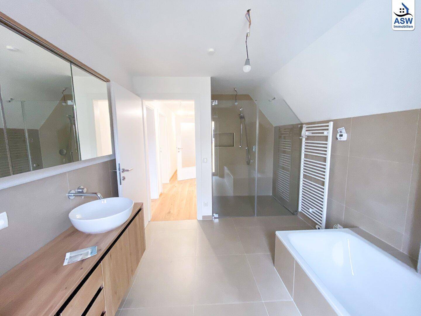 Modernes Badezimmer im Dachgeschoss mit Badewanne, großer Dusche und Doppelwaschbecken.