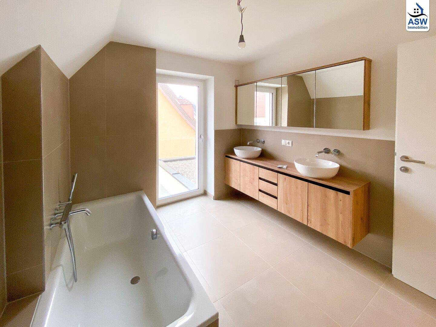 Geräumiges Badezimmer im Dachgeschoss mit Badewanne, Doppelwaschbecken und Fenster.