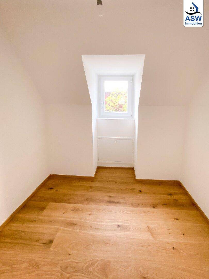 Kleines, helles Zimmer im Dachgeschoss mit Eichenparkett und einem Dachfenster.