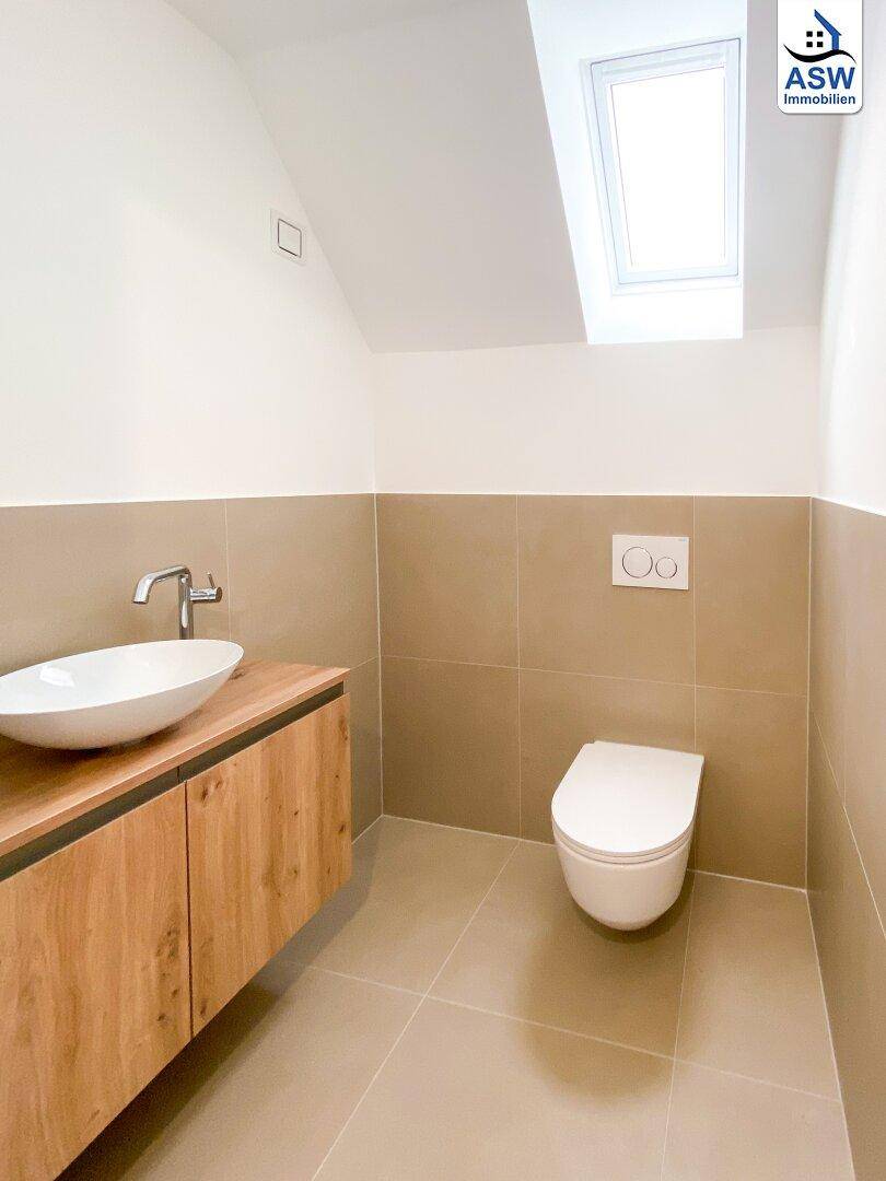 Modernes Gäste-WC im Dachgeschoss mit schwebendem Waschtisch, Wand-WC und Dachfenster.