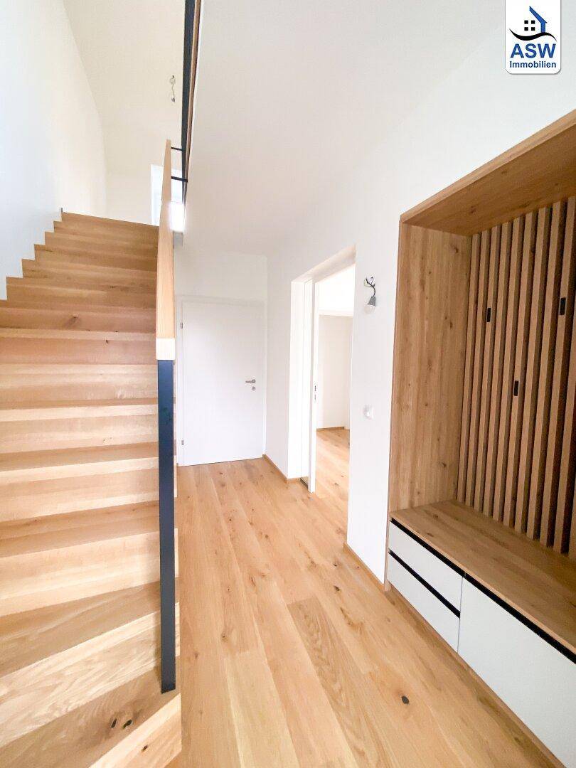 Heller Eingangsbereich mit Holztreppe, Eichenparkett und integrierter Garderobe.