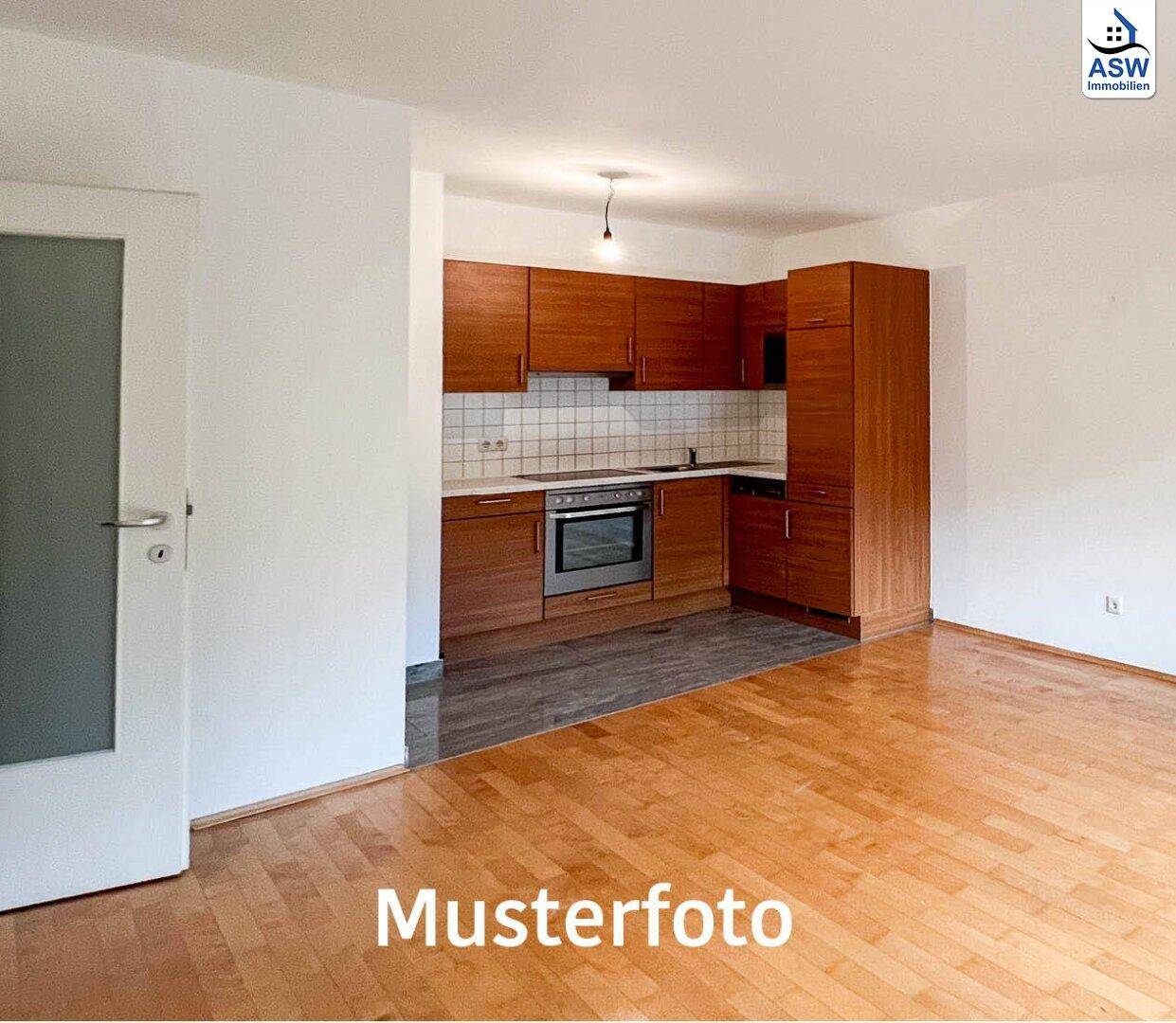 Offene Küche mit Holzschränken und integrierten Geräten, angrenzend an einen Wohnbereich.