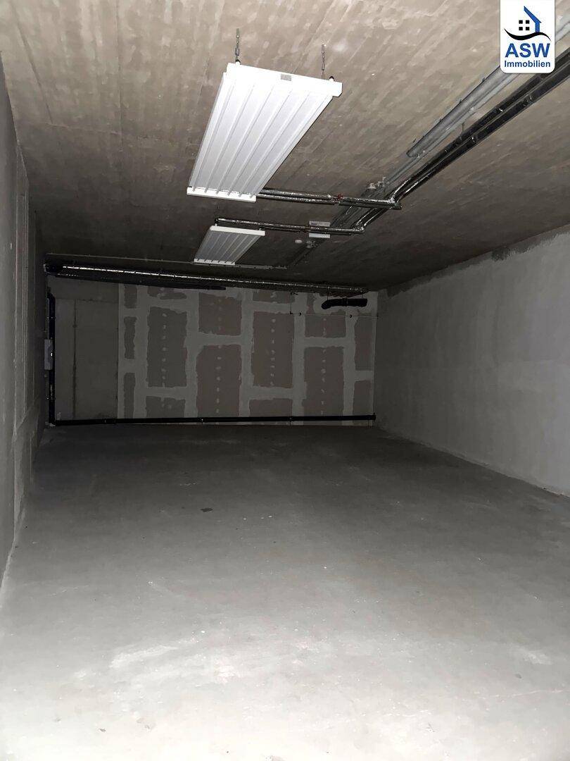 Langer, leerer Lagerraum im Kellergeschoss mit Betonboden und Decke, ausgestattet mit einfachen Leuchtstoffröhren.